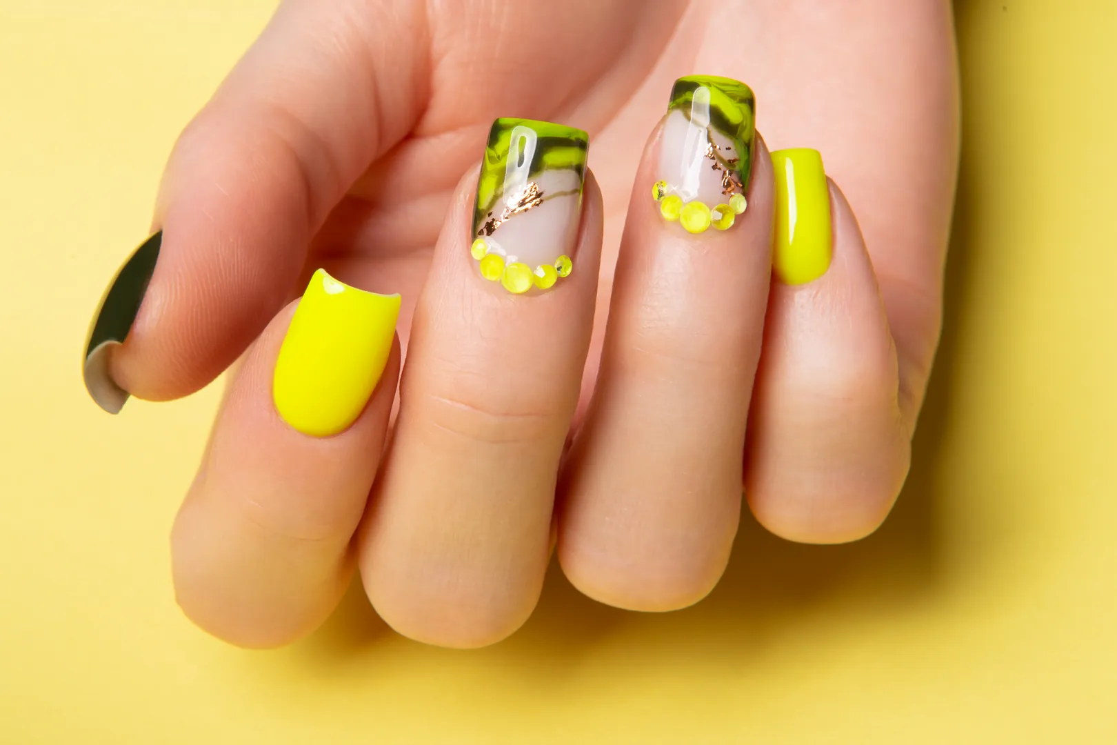 Neonsárga és zöld márványos nail art kövekkel díszítve